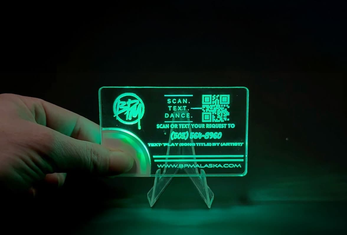 A person displays a glowing light up table card on a stand.
