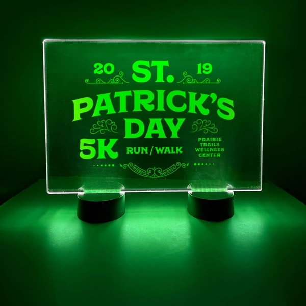 A green illuminated acrylic sign displaying the words "St. Patrick's Day" in festive lettering glowing in green neon