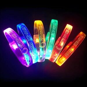 six laser engraved LED bracelets with "Camp Kid Jam" and logo all glowing a different LED color in a rainbow