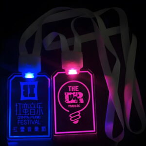 Two custom LED badges on nylon lanyards side by side, badge on left is lighting music festival logo in bright blue and badge on right is lighting a music logo in hot pink