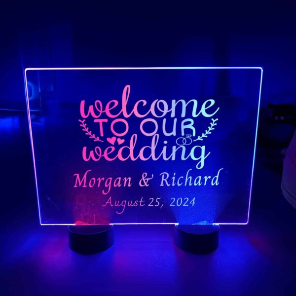 Bright acrylic table sign centerpiece displaying "Welcome to Our Wedding" illuminated with blue and red led lights