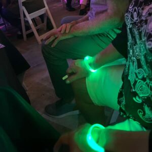 A man wearing a green glowing wristband at a concert