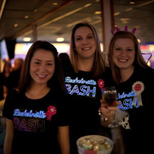Three women at bachelorette party wearing custom light up shirt while holding drinks and smiling