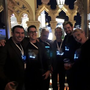 A cheerful group of people in glowing LED t-shirts poses for a nighttime photo