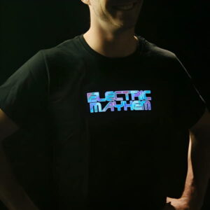 Smiling guy with hands on hips sporting a light up shirt with the words "Electric Mayhem" illuminating