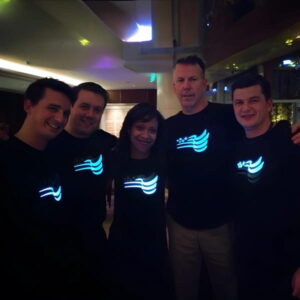 group of five colleagues posing in their custom company logo light up shirt design