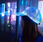 A woman wearing a blue glowing hat looking in a reflection