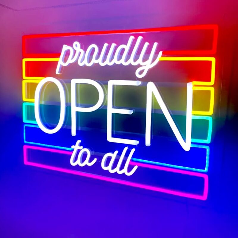 Bright neon sign displaying "Proudly Open To All," highlighting a commitment to inclusivity and openness.